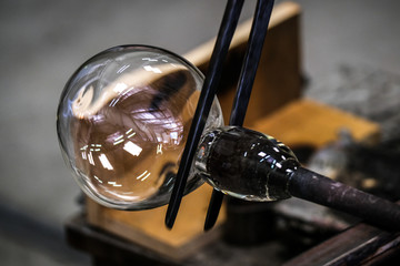 Artist glass blower working glass paste on his workbench. A glass crafter is burning and blowing an art piece