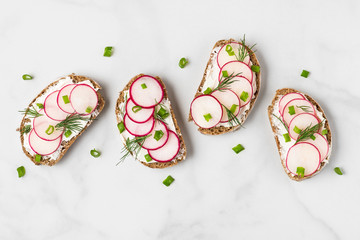 Healthy spring toasts with radish, curd cheese onion and dill on white marble table. top view - obrazy, fototapety, plakaty