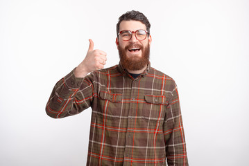Naklejka premium Smiling bearded man is showing thumb up or like gesture over white background.