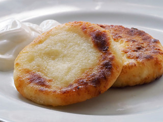 Cottage cheese pancakes are on a plate.  Toasted cottage cheese pancakes with a Golden crust lie on a white plate