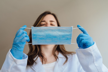 Confident young surgeon doctor in latex protective gloves wearing medical mask on face. Man...