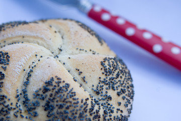Mohnbrötchen und rotes Messer mit weißen Punkten liegen auf einem Teller