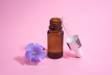 A glass dropper bottle on the pink background.