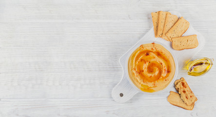 Healthy homemade creamy hummus with olive oil and crispbread on white wooden background. Healthy and diet food concept