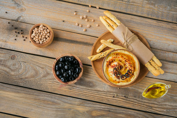 A bowl of chickpeas homemade hummus with olive oil, black olives and crispbread