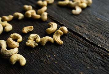 Cashew nuts scattered on the wooden vintage table. Cashew nut is a healthy vegetarian protein nutritious food.