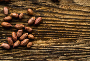 Obraz na płótnie Canvas Peanut nuts scattered on the wooden vintage table. Peanuts nut is a healthy vegetarian protein nutritious food.