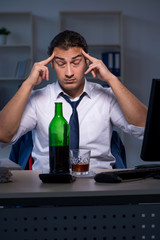 Alcohol addicted businessman working late in the office