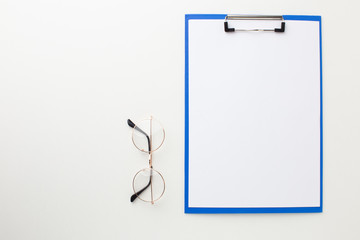 Empty file folder on white desk with glasses for sight. Top view