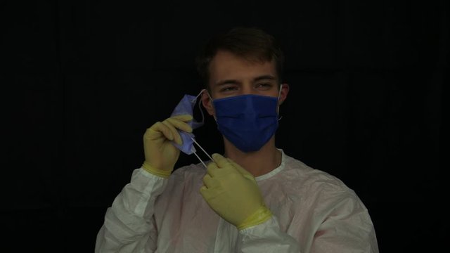 A caucasian man shows how to take off tripple protective mask