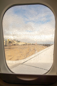 An airplane window with a tropical storm outside and raindrops. 