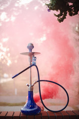 Hookah outdoors on a background of colored smoke