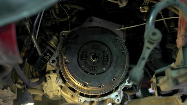 Car mechanic is unscrewing clutch. Car service worker with diry hands using electrical screwdriver to unscrew car clutch.