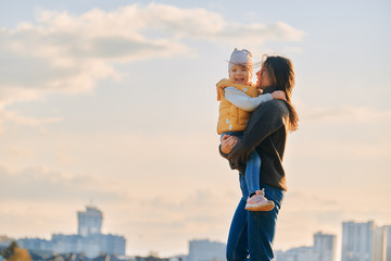 portrait of mom with a daughter in her arms against the backdrop of the cityscape
