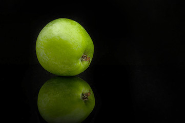 Fototapeta na wymiar Green apple with reflection on a black background