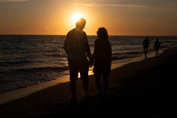 Para ludzi oglądający zachód słońca nad morzem.