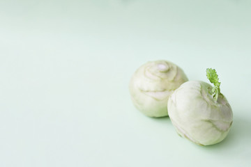 Fototapeta premium Two kohlrabies on a paper background. Light mint green background. Wallpaper. Copy space, space for text