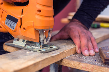 A man is sawing plywood with a jigsaw.