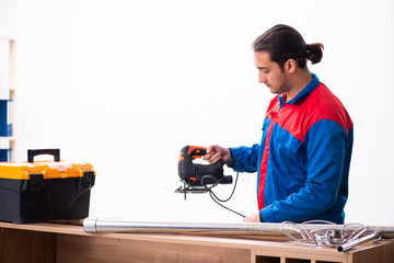 Young handsome male carpenter working indoors