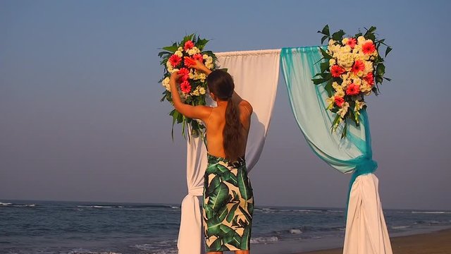 Decorator working with flowers composition for wedding arch on ocean beach