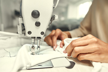 Stitching Up. Close up of seamstress hands. She is sitting and sewing. Dressmaker working on the sewing machine. Tailor making a garment in her workplace
