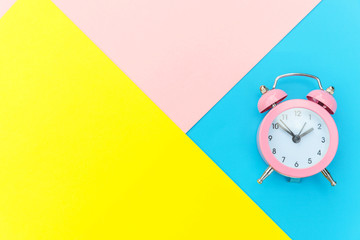 Ringing twin bell classic alarm clock isolated on blue yellow pink pastel colorful geometric...