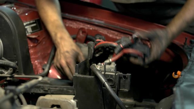 Mechanic with dirty hands uninstalling and fixing car engine details. Professinal repairman in a car service center repairing a car motor.