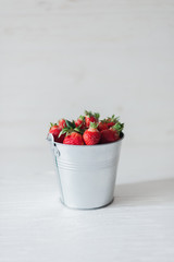 Juicy fresh strawberries in a metal bucket on a white background