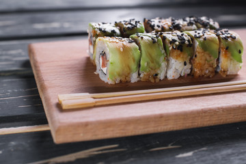Sushi with salmon on a wooden board on a dark wooden background