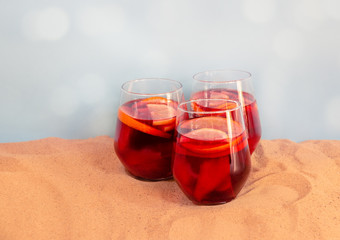 Red wine sangria with fruits in glasses on sand beach. Selective focus.