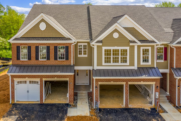 Elevated view of almost finished luxury townhouses with two single car garages, brick and shake and...