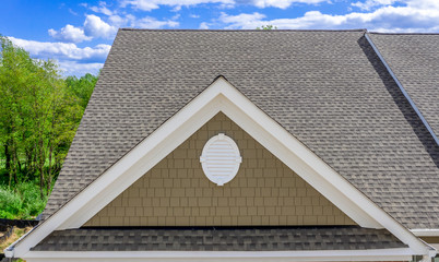 Aerial view of a single gable roof with decorative, elegant colonial white oval gable vent on a...
