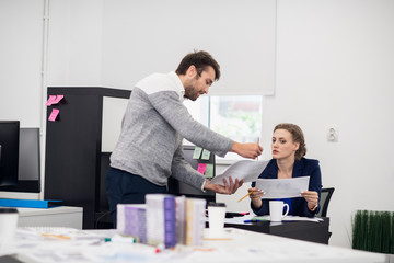 Two office workers, a man and a woman, discussing something. The