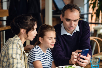 Fototapeta premium A father is showing somthing to his family on his phone
