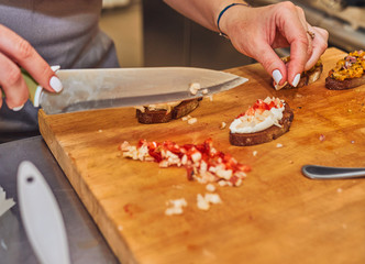 The process of making delicious bruschetta on crispy toasted bread. Female hands