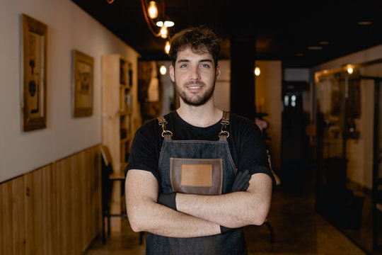 camarero barista sonriente en una cafeteria, tiene los brazos cruzados