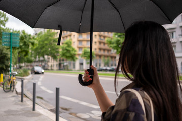 Une femme de dos qui tient son parapluie dans une rue de la ville de Grenoble 