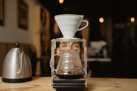 barista mirando a trav&eacute;s de un filtro de caf&eacute; v60 en su cafeter&iacute;a