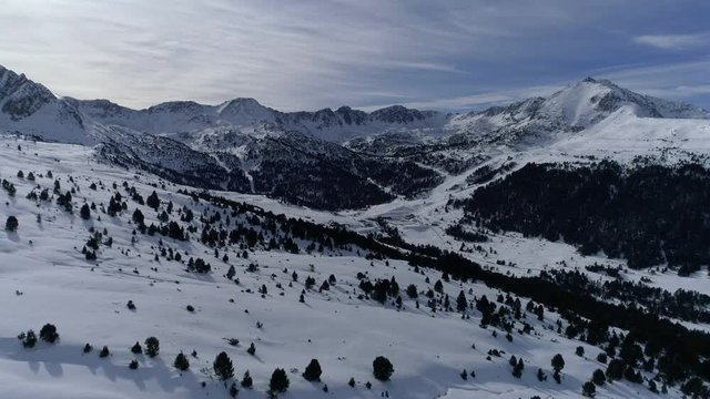 AERIAL DRONE FORWARD SMOOTH MOVEMENT INTO SNOWED PYRENEES VALLEY WITH WOODS, GRAU ROIG, GRANDVALIRA, ANDORRA 