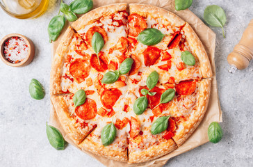 Pepperoni pizza with basil on a rustic background.