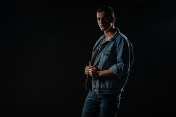 Picture of a young handsome macho man with abs and open denim jacket and jeans.