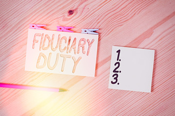 Conceptual hand writing showing Fiduciary Duty. Concept meaning A legal obligation to act in the best interest of other Colored crumpled papers wooden floor background clothespin