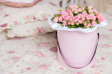 Spray roses in a round box on the bed.
