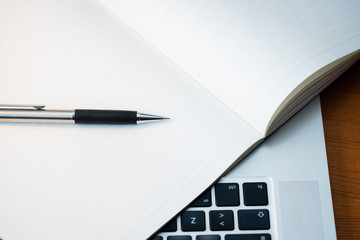 Keyboard of a Laptop from Above with a Notepad and a Pen.