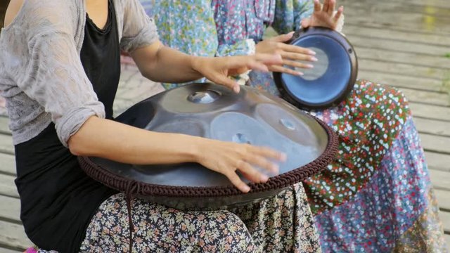 Close-up of girl's hands playing tank drum or hang and drum on ethnic open air concert. Relaxation, folk, meditative and traditional ethnic music concept. 4K