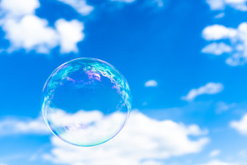 Blown bubble and blue cloudy sky