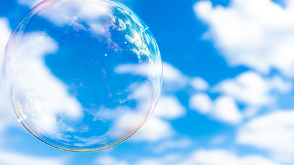 Blown bubble and blue cloudy sky