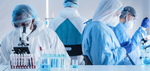 african american biochemical research scientist and team working with microscope for coronavirus...