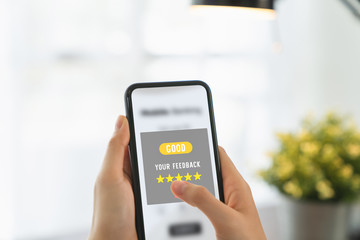 Hand holding smartphone and rate your feedback and show five star on application.