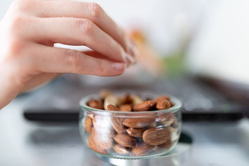 The woman works remotely, using a laptop, eating peanuts with her hands.
Hands eating